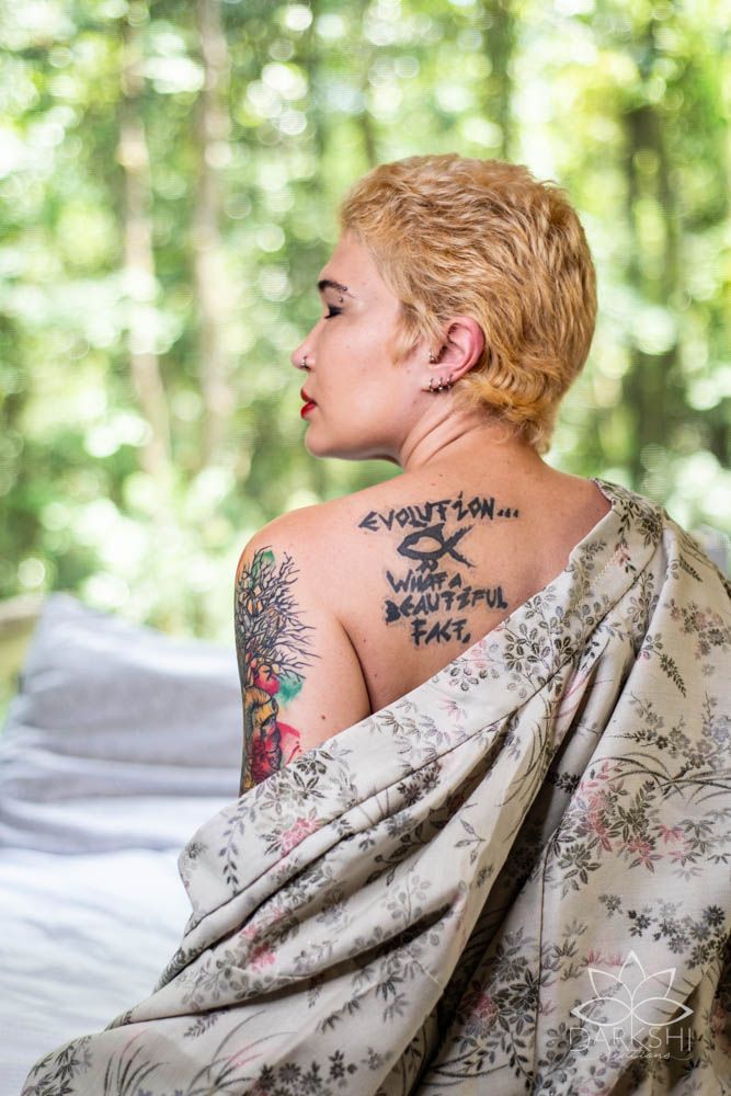 Close-up profile view showing neck tattoos against a soft natural background.