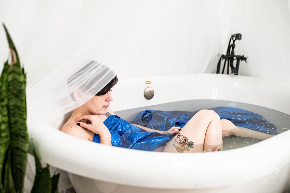 Person relaxing in white bathtub with visible arm and leg.