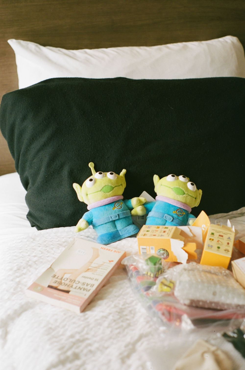 Cute plush toys and colorful decorative items arranged on white bedding.