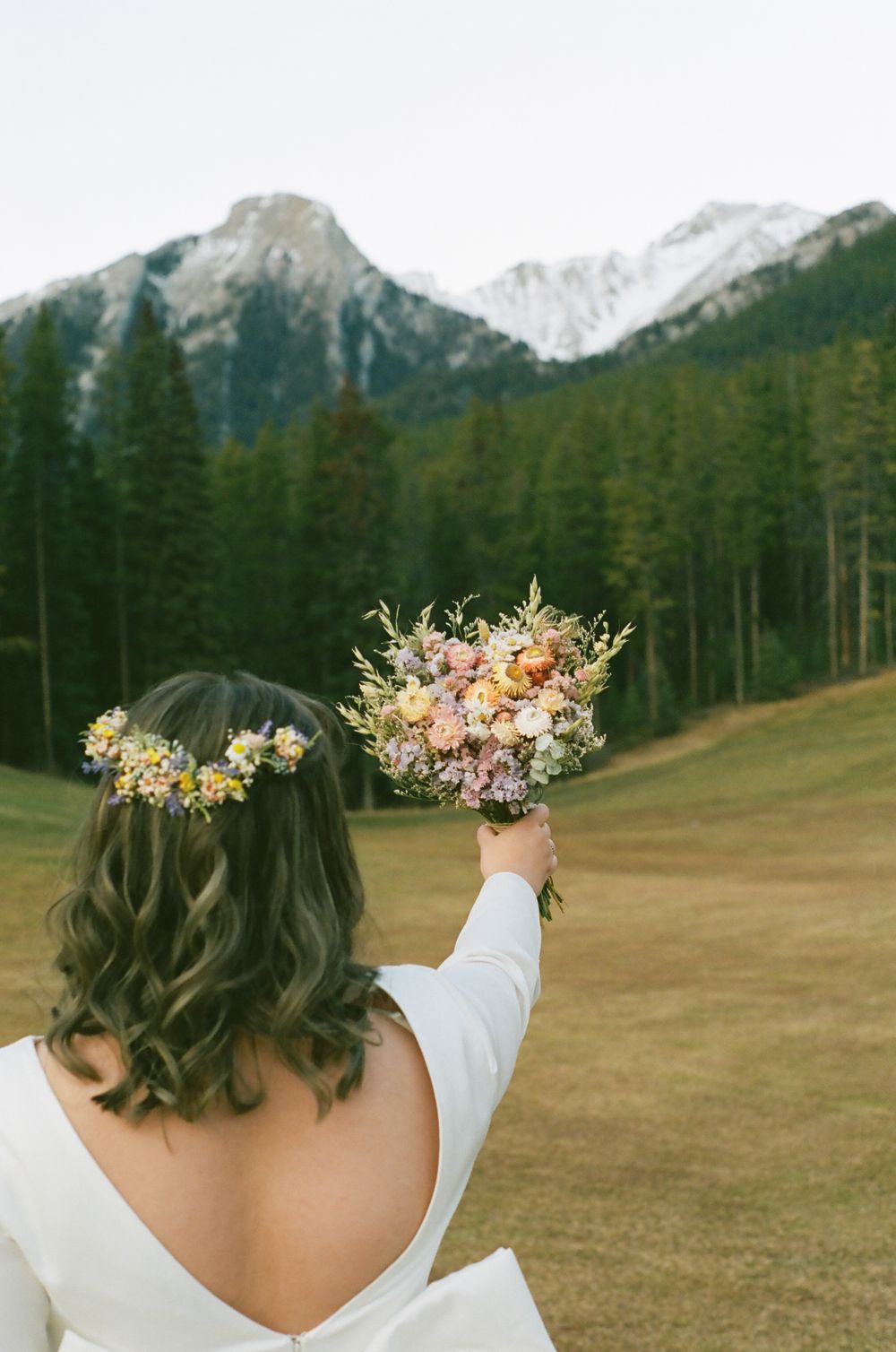 A series of artistic wedding photos showing bouquets against a mountain landscape with evergreen trees.