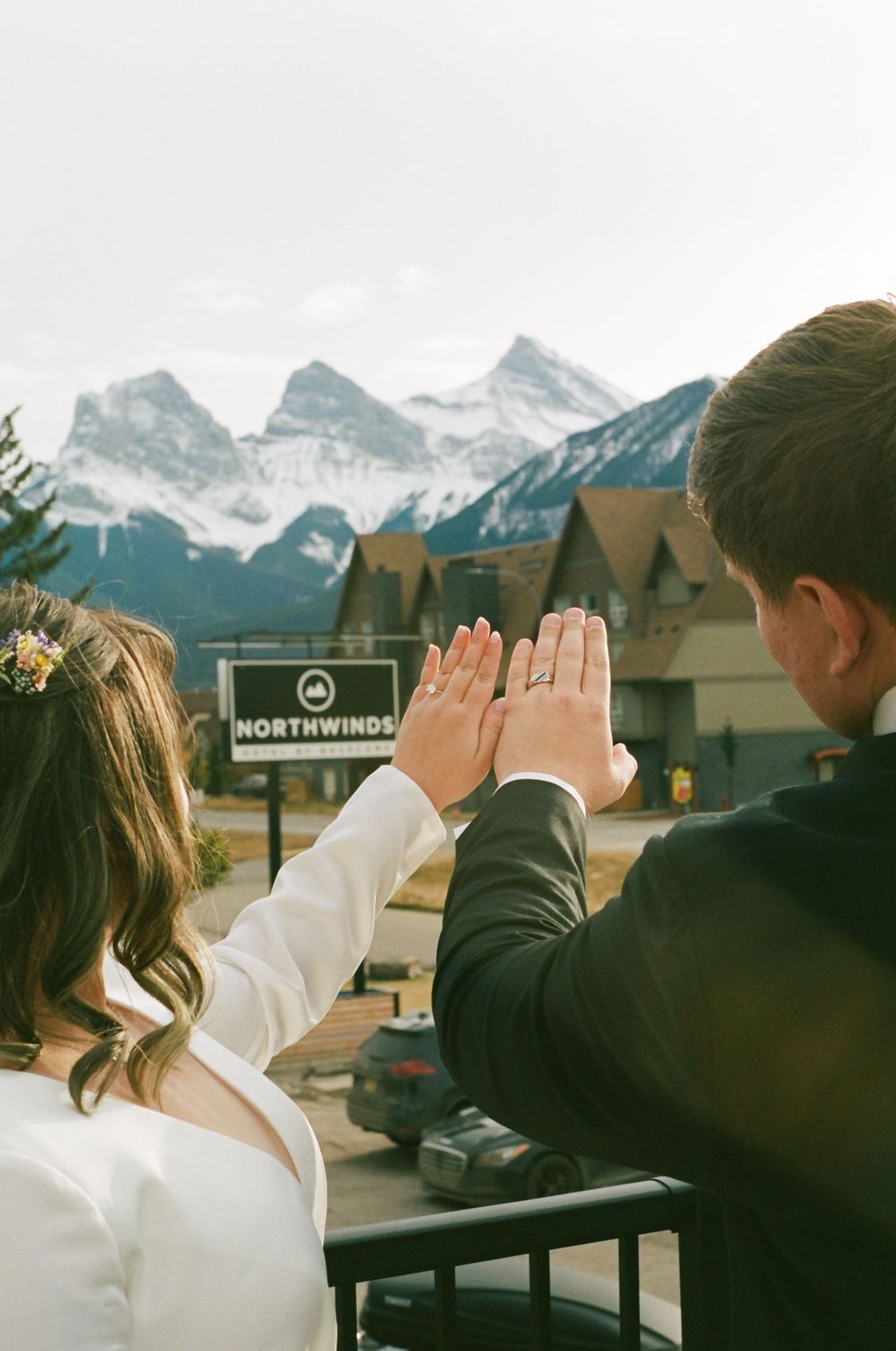 Wedding couple poses playfully against stunning mountain backdrop at a resort.