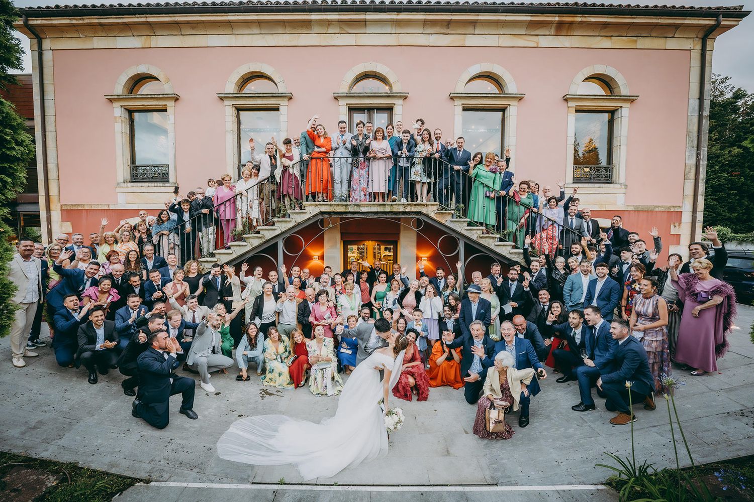 Invitados celebrando y saludando durante el cóctel de una boda en Asturias con los novios en primer plano