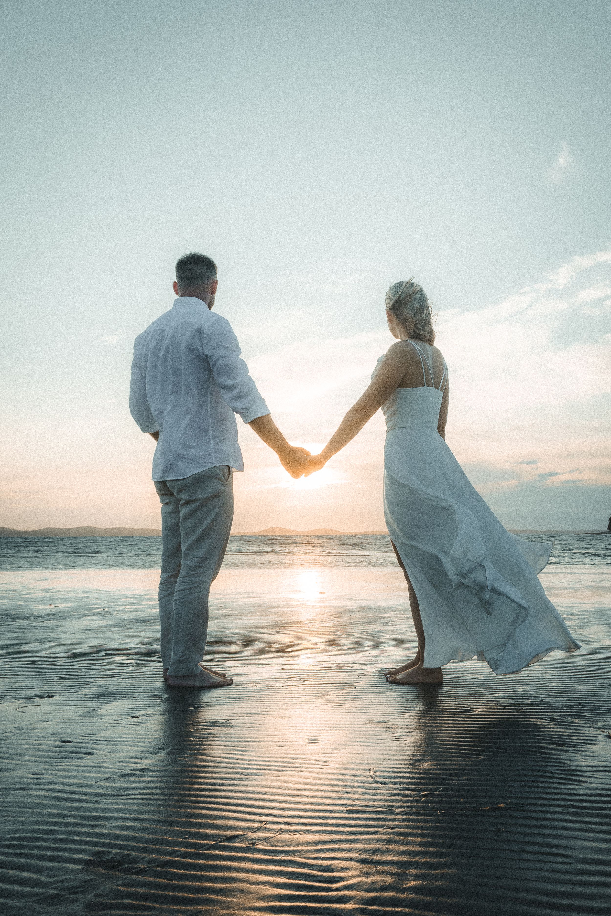 Couple standing on the beach during sunrise on elopement wedding day