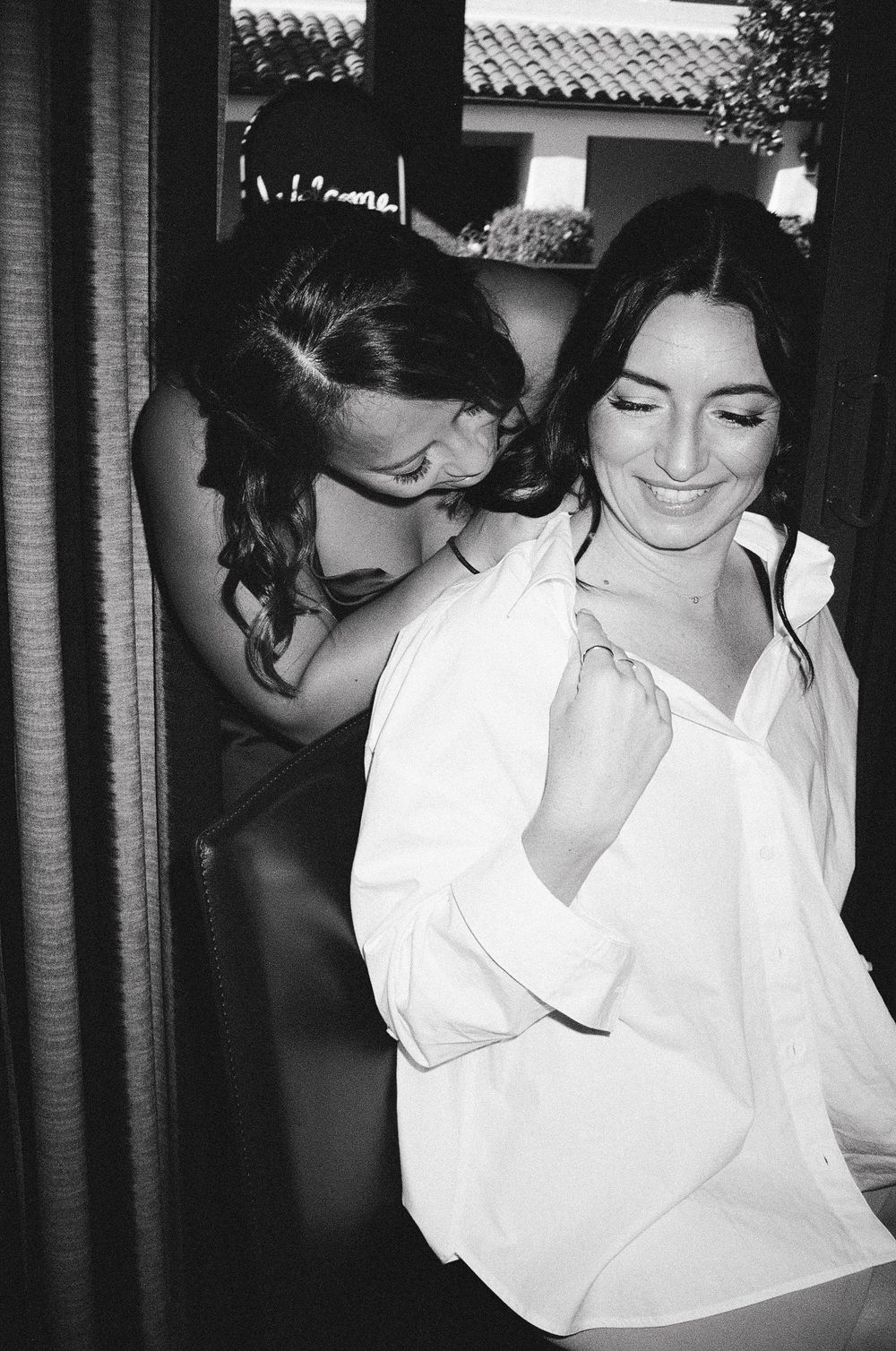 A black and white candid photograph shows two people sharing an intimate moment in casual attire.