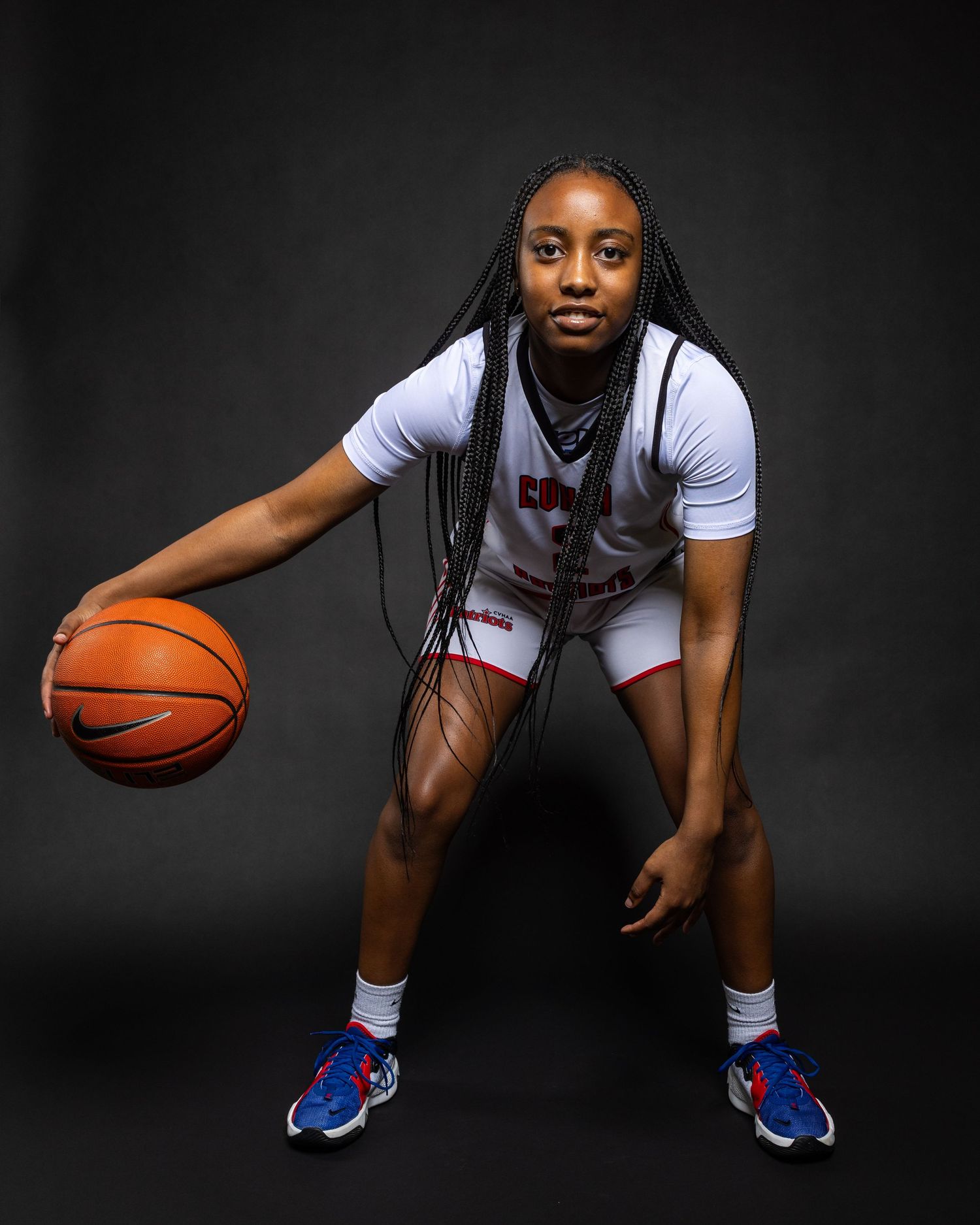 Basketball player in white jersey crouches in defensive stance against dark background in progressive action sequence.