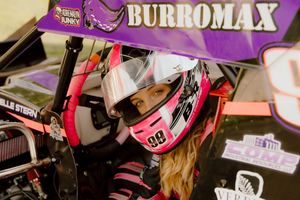 Female race car driver in pink helmet sitting in purple Burromax sprint car number 88.