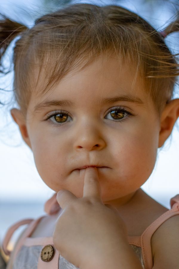 toddler girl with finger in her mouth wearing pigtails on the york river in yorktown virginia