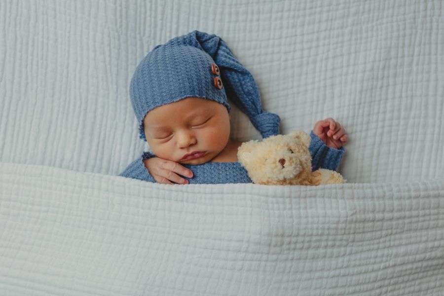 newborn baby boy sleeping with yellow teddy bear wearing a blue sleep cap
newborn home session servicing coastal virginia