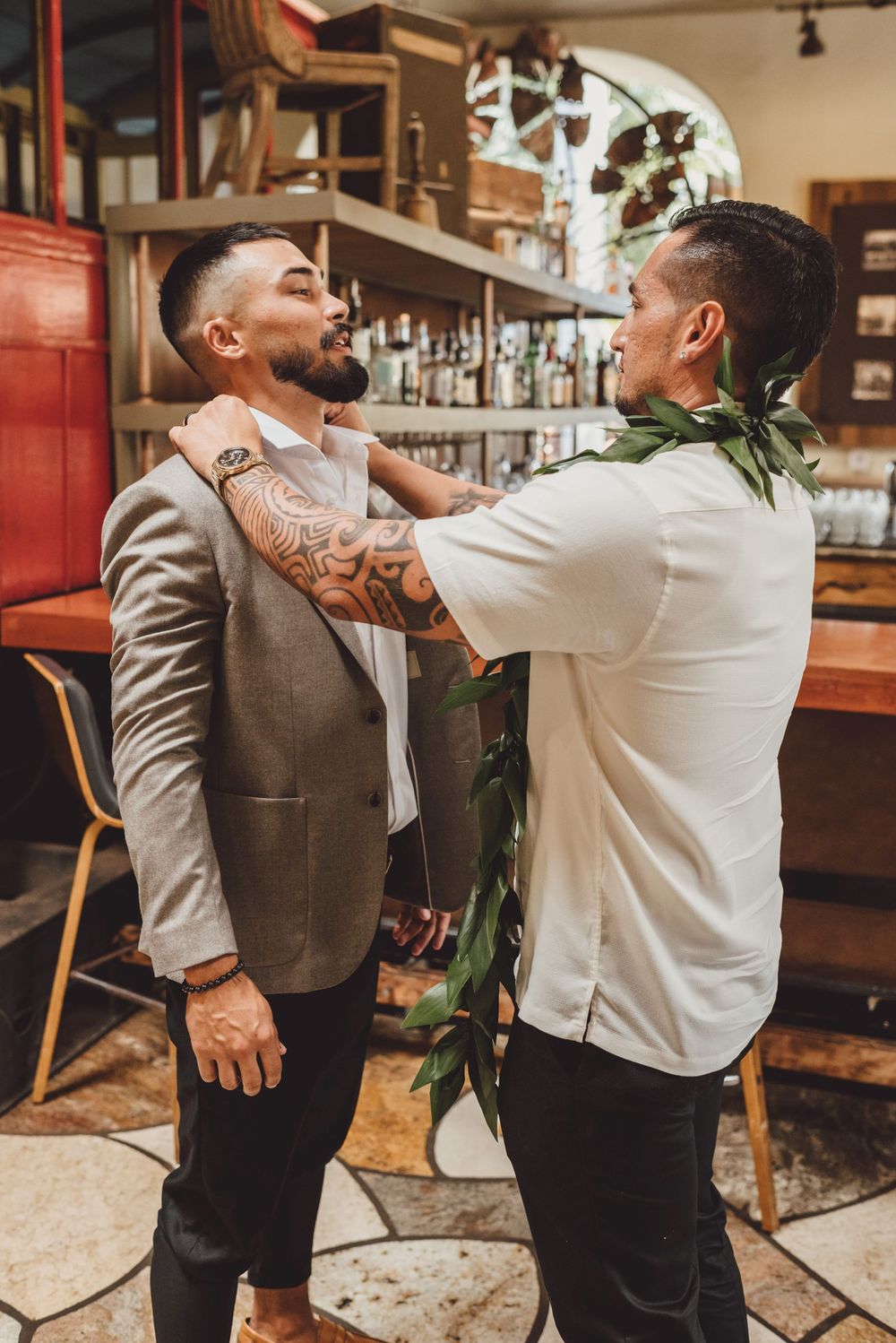 Two people in formal attire playfully interact and laugh together at a bar or restaurant venue.