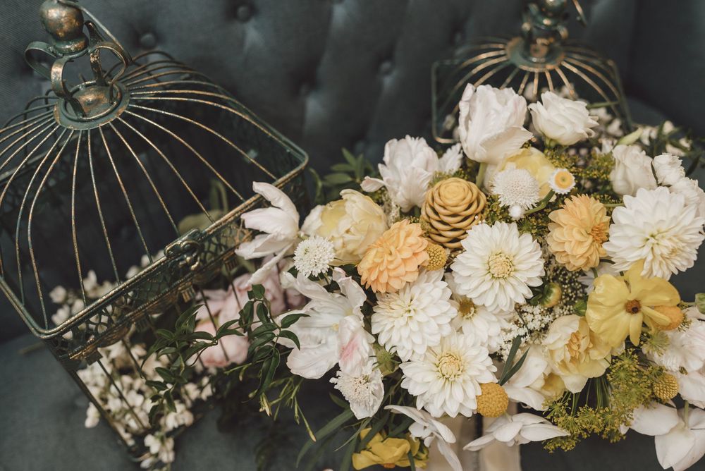 Decorative birdcages adorned with delicate white and yellow flowers create an elegant vintage-inspired display.