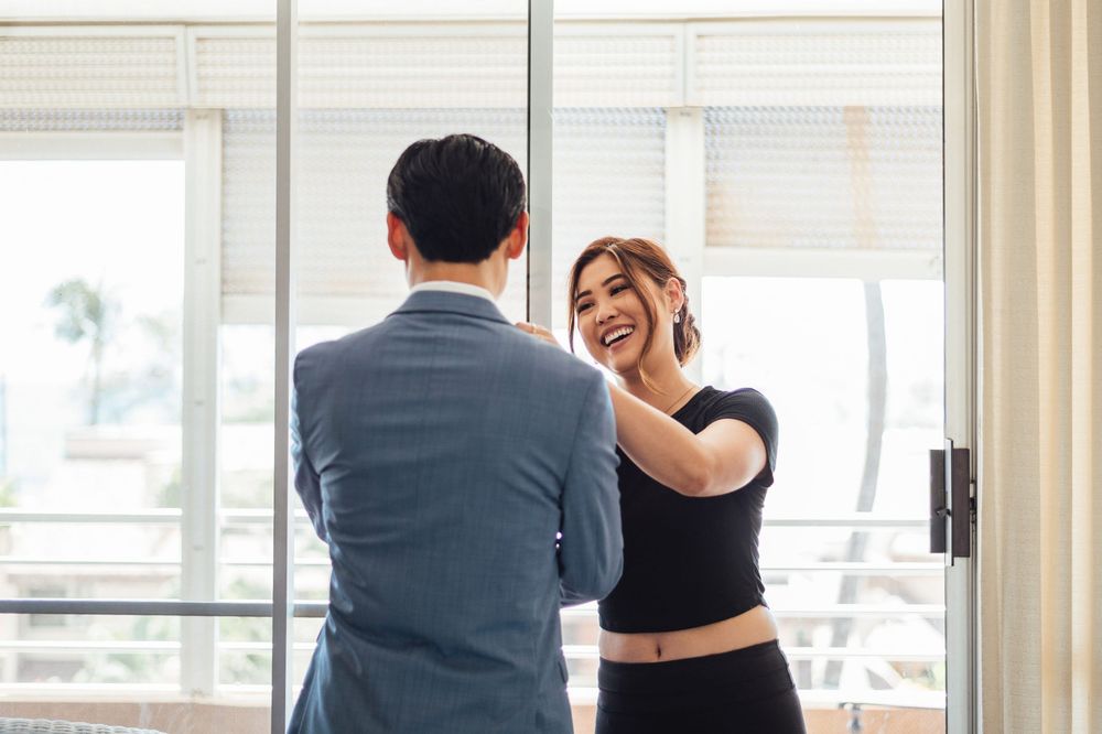 Two people stand by large windows in a bright modern office space with natural lighting.