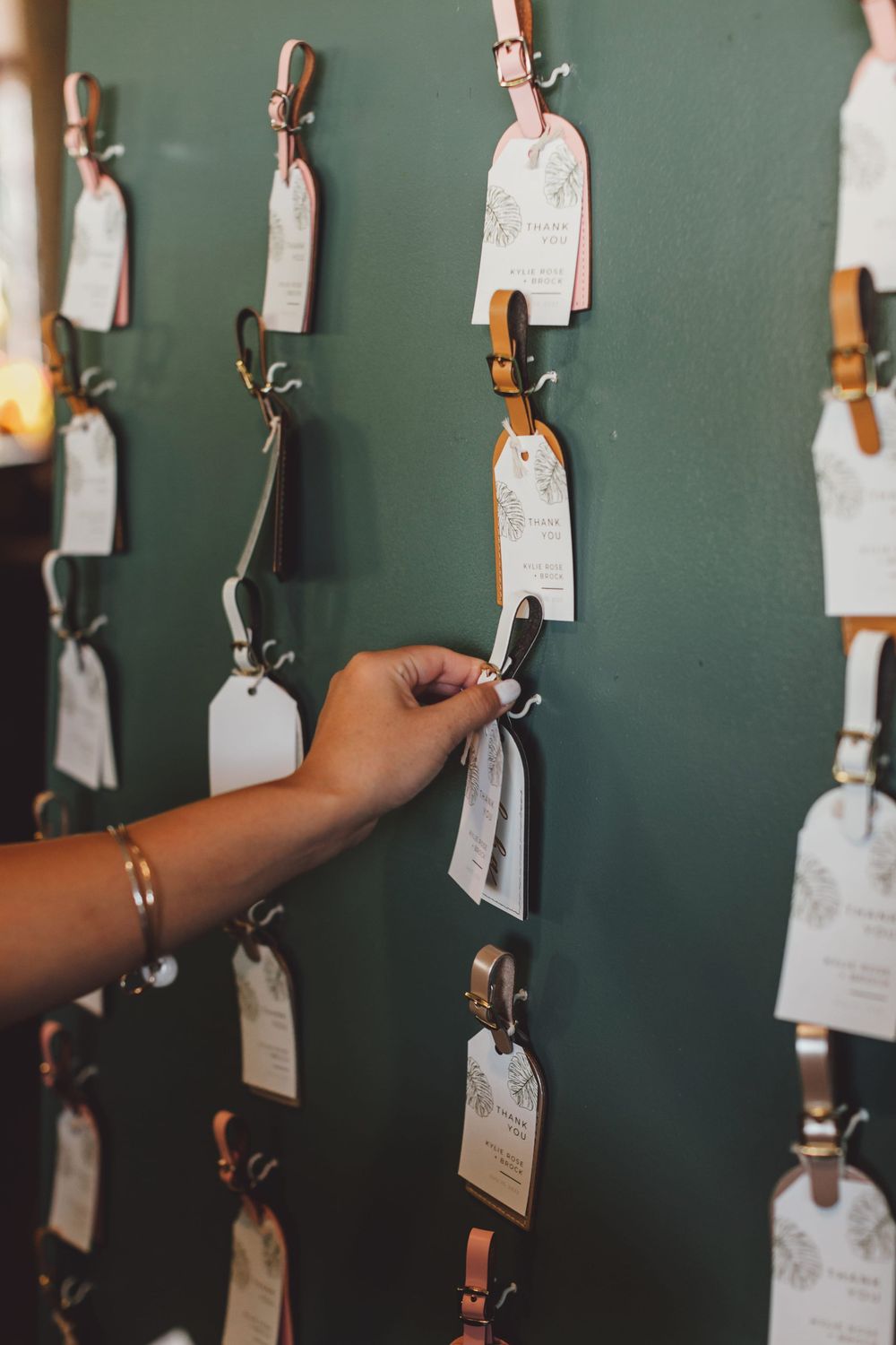 Multiple paper tags with strings hang from hooks against a green wall in a dimly lit room.