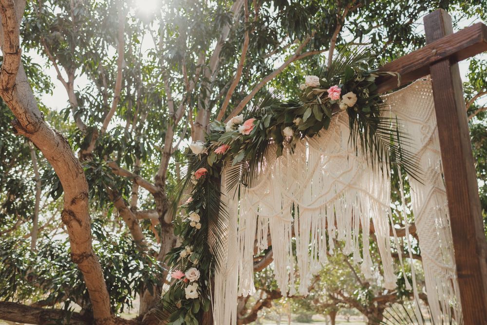 Outdoor wedding venue decorated with hanging greenery and string lights creating a romantic atmosphere.