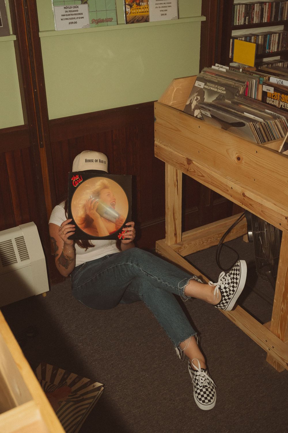 Person lying on floor between wooden bookshelves in what appears to be a library or bookstore.