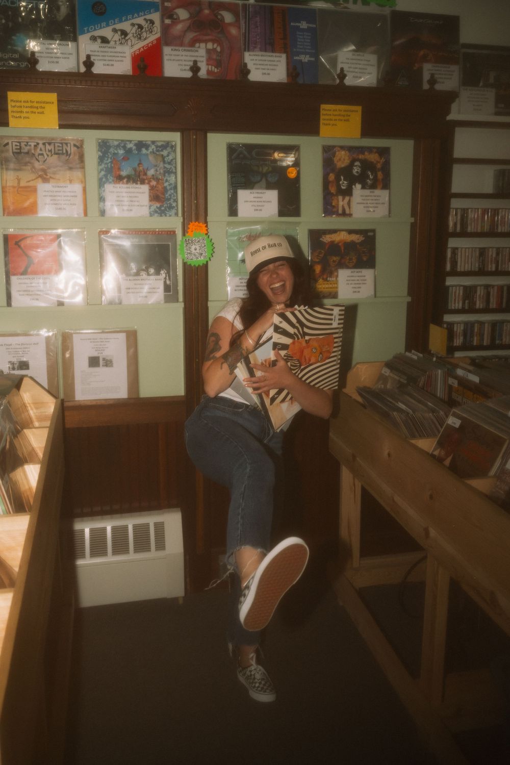 Customer flipping through vinyl records in a dimly lit record store with wall displays.
