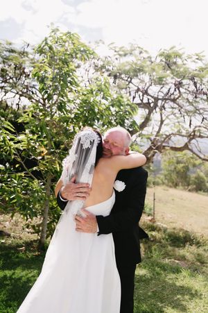 Romantic embrace between newlyweds in a garden setting with sunlit trees in the background.