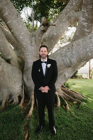 A sequence of photos showing a person in a black tuxedo standing in front of a large tree trunk.