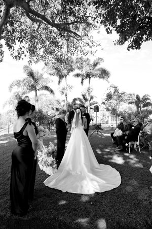 Black and white wedding ceremony photos under palm trees with guests looking on.