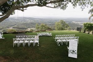 White ceremony chairs set up on a hillside overlooking a scenic valley landscape.