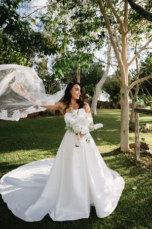 Flowing white wedding dress billowing in the breeze during outdoor photo session.