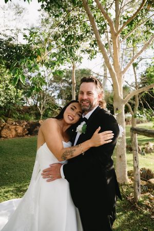A romantic wedding portrait captured in a garden setting with natural sunlight.