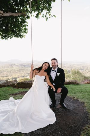 Couple relaxing on grassy hillside overlooking scenic valley view.