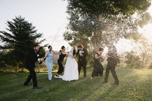 Wedding party silhouettes against golden sunset in outdoor garden setting.