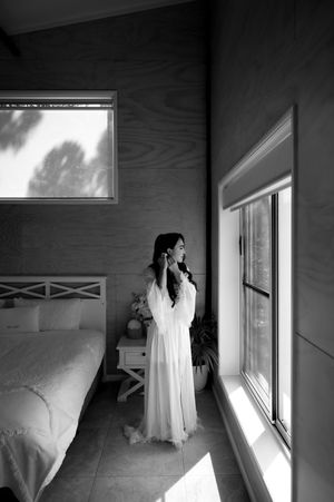 A series of black and white photos showing a white wedding dress hanging in a sunlit room.