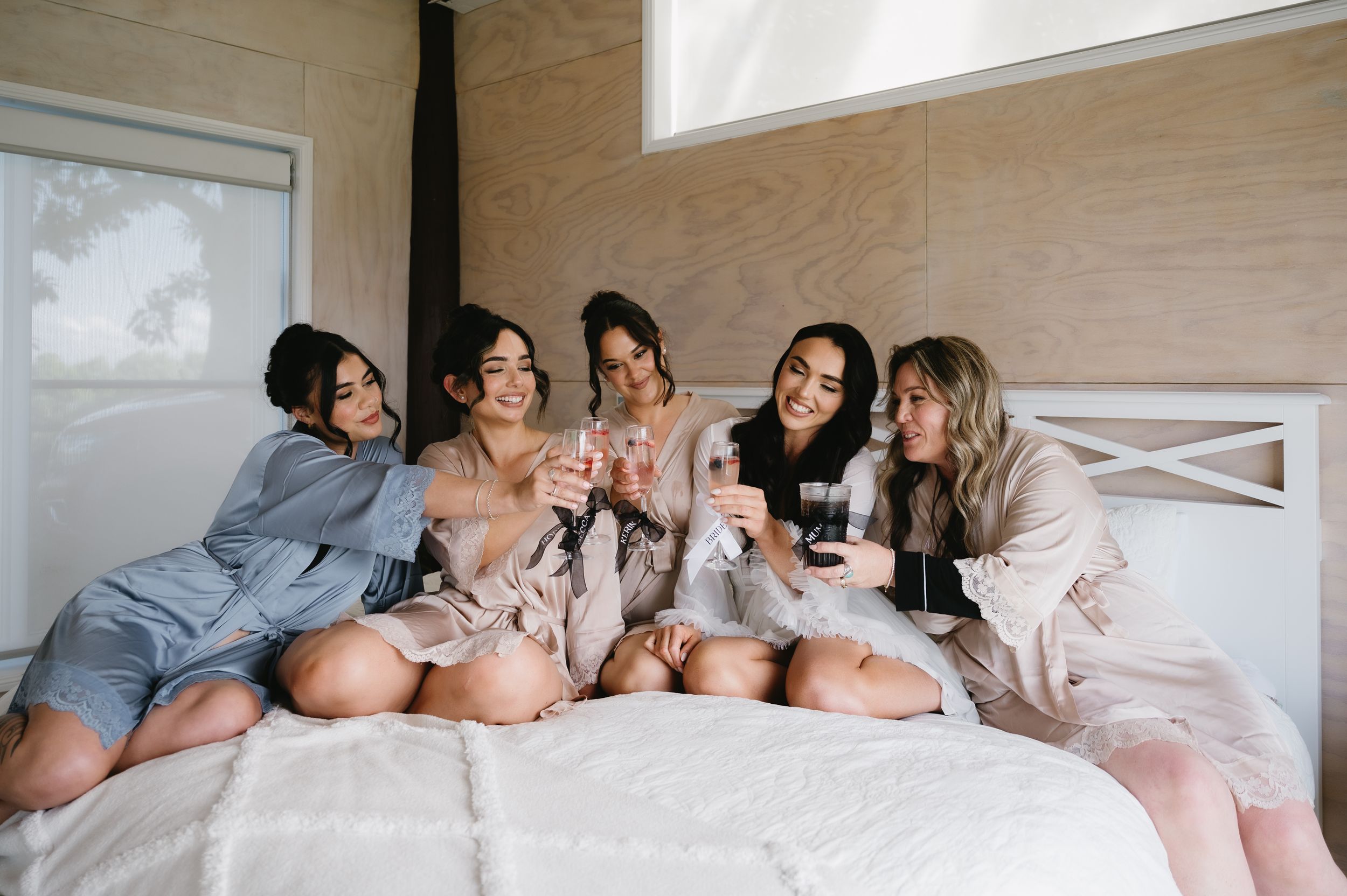 Group relaxing together on a cozy bed with white linens in a bright sunlit room.