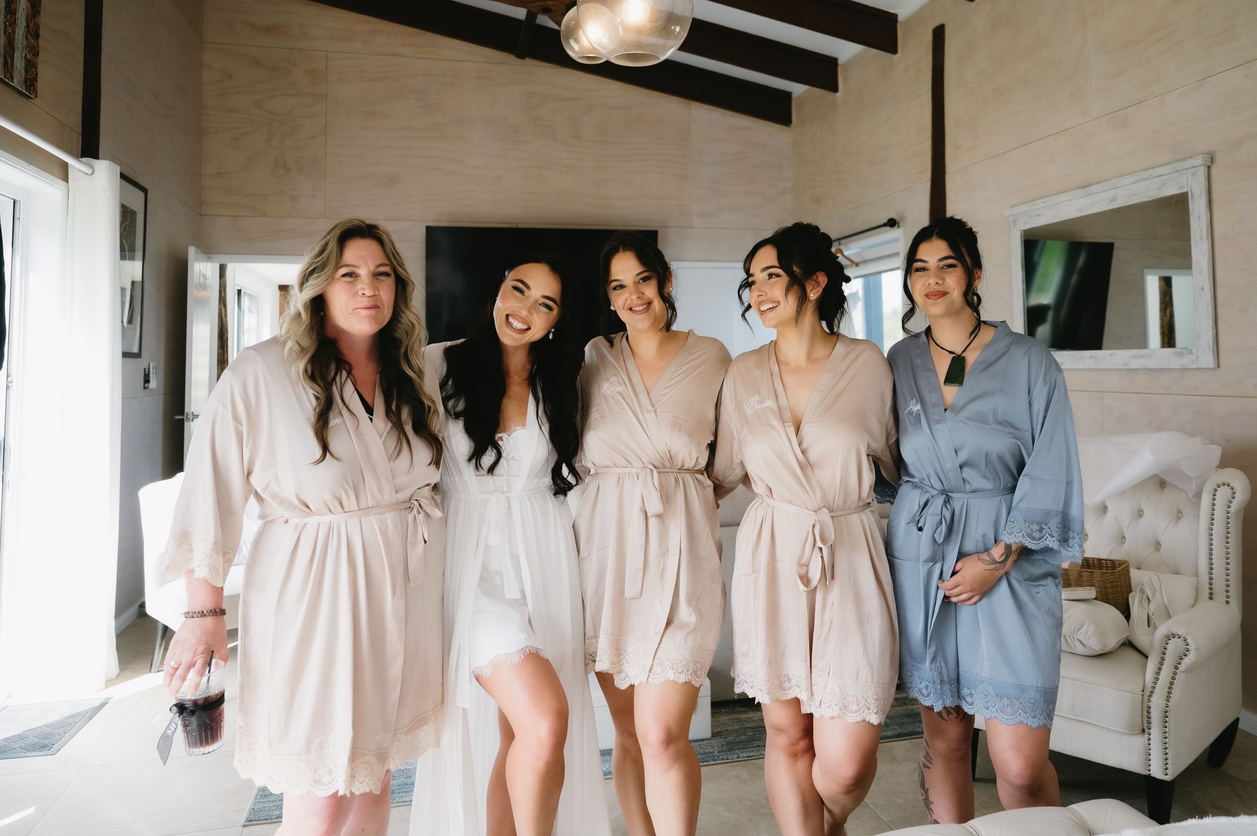 A group of people wearing matching pastel-colored loungewear and sleepwear stand together in a cozy bedroom setting.