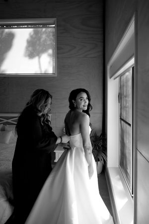 A series of artistic black and white photos showing preparations with a wedding dress in a bright interior space.