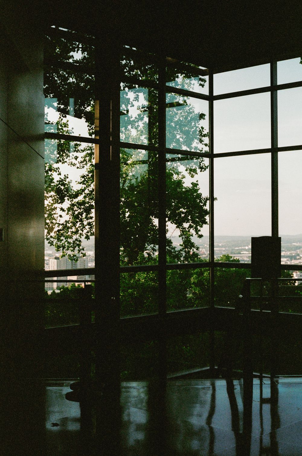 Modern interior space with floor-to-ceiling windows overlooking a scenic landscape at dusk.