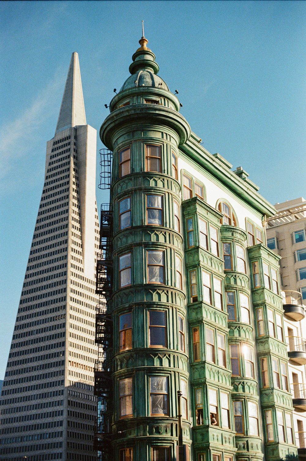San Francisco cityscape featuring the Transamerica Pyramid and historic green Victorian architecture.