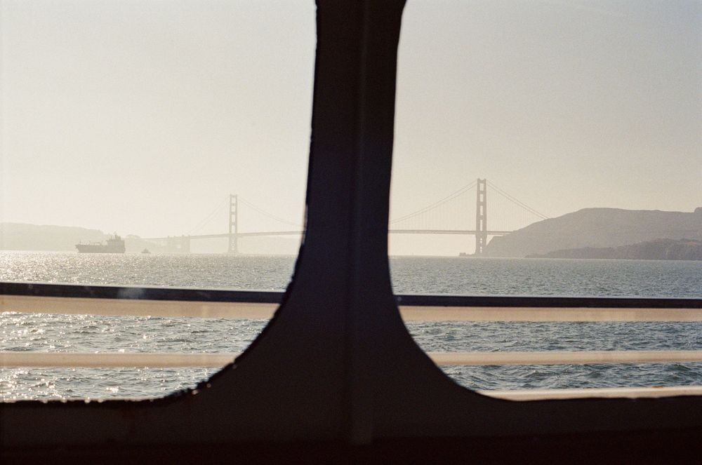 Silhouette of Golden Gate Bridge towers viewed through window frame at sunset.