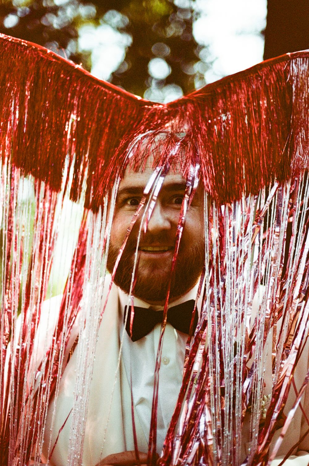 Red metallic tinsel decorations create a shimmering curtain effect against a dark background.