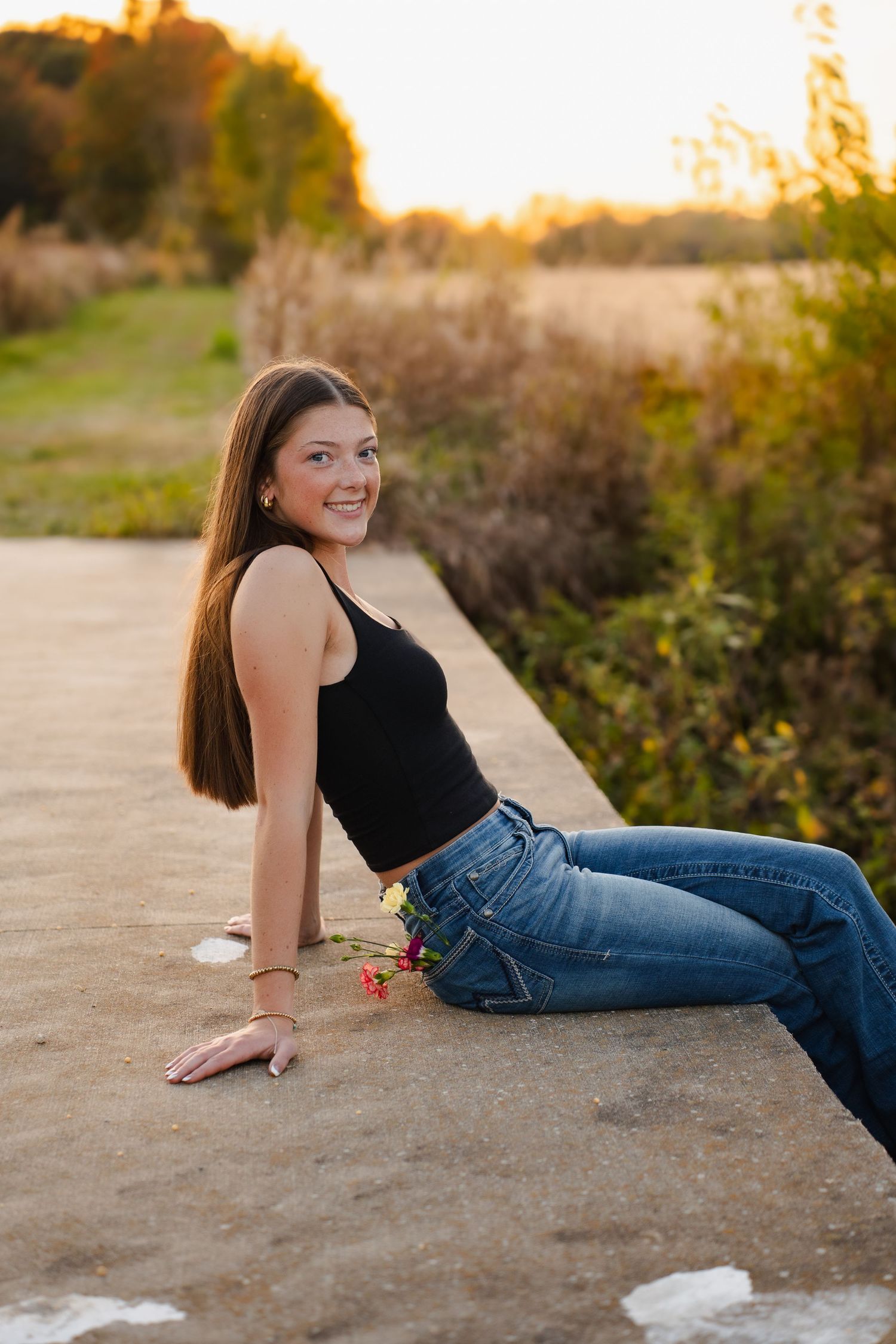 Person relaxing on concrete surface in casual outfit during golden hour.