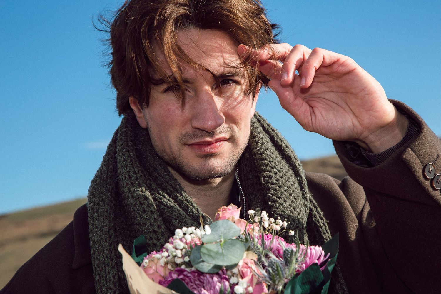 A series of photos showing a person wearing a green scarf and holding pink flowers in various poses against a blue sky.