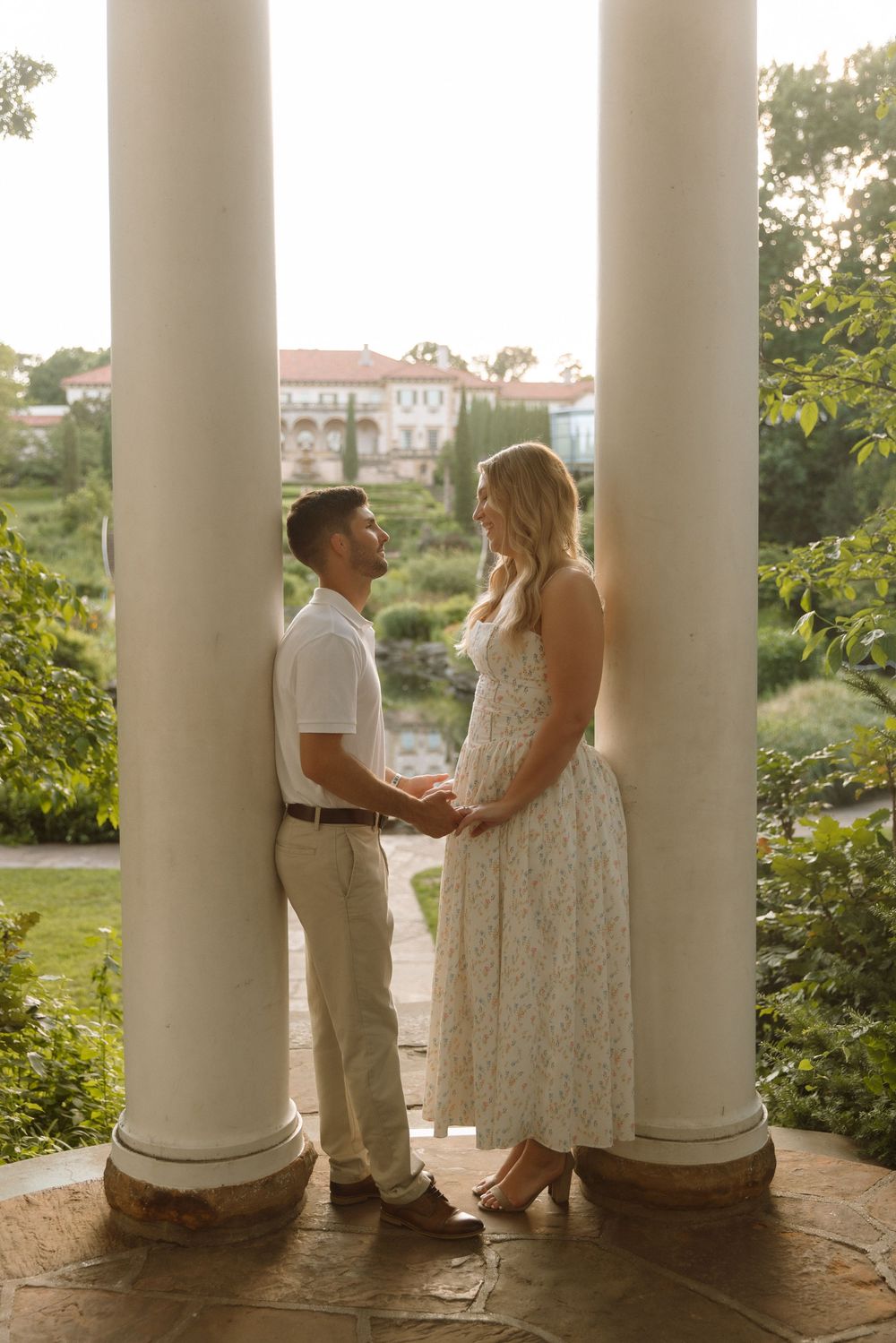 A series of romantic engagement photos captured between white columns with a scenic coastal backdrop at sunset.