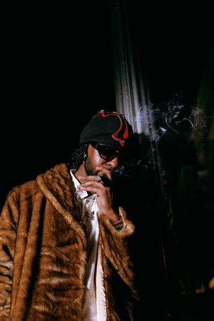 Dramatic sequence of someone in a brown fur coat smoking a cigarette in dark moody lighting.