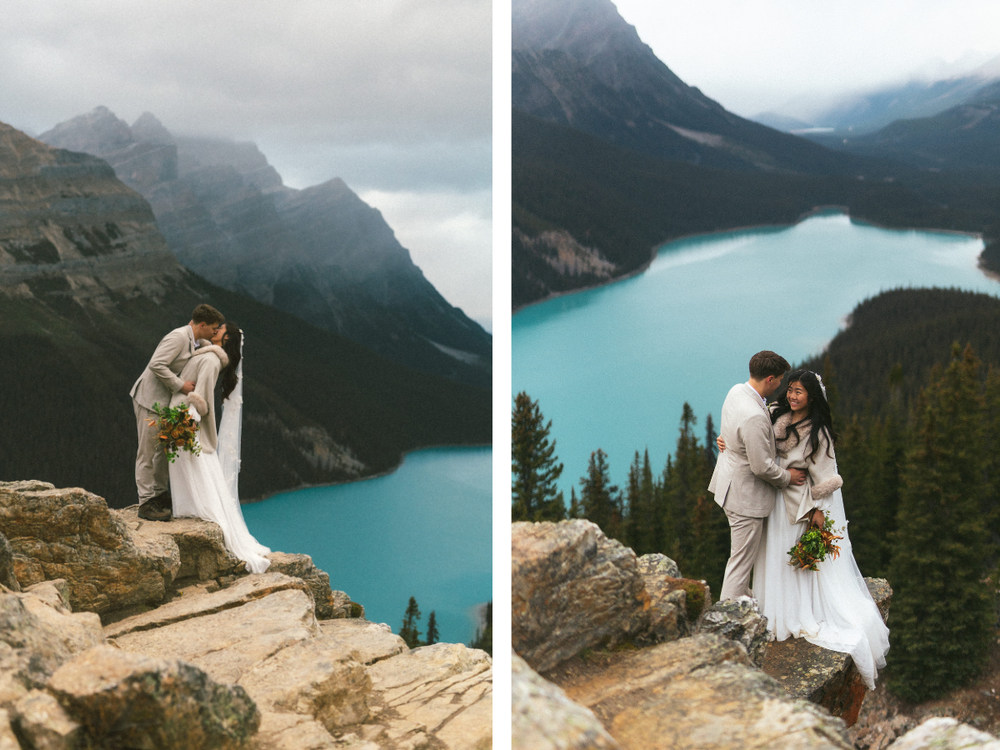 bride and groom kiss on the trail to Peyto Lake in Banff with mountain peaks behind them