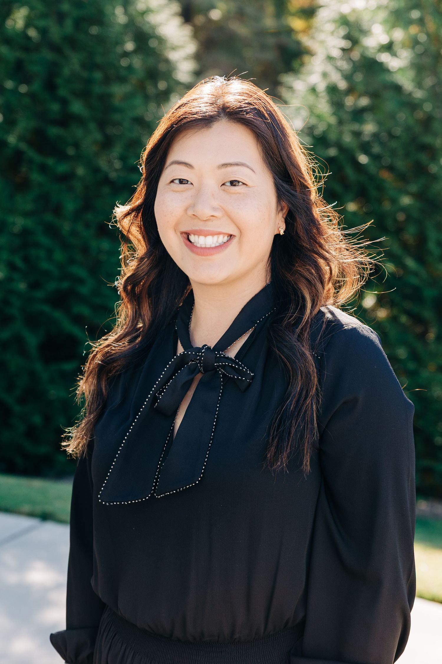 Professional outdoor portrait series showing a person in a black blouse against a natural green background.