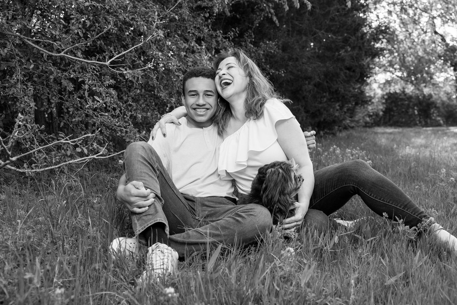 A couple relaxes together on grassy ground in a romantic outdoor photoshoot.