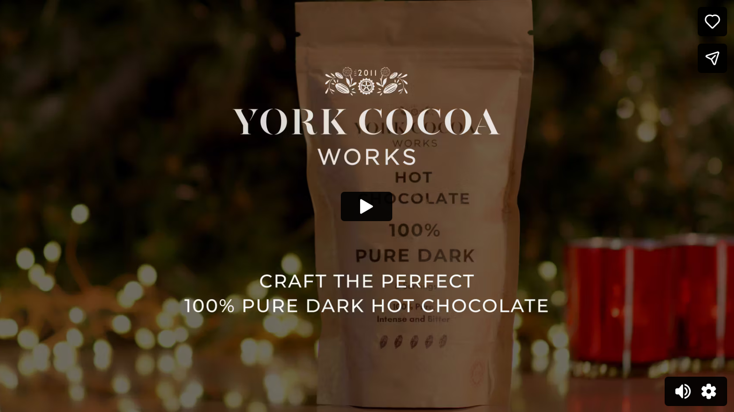 Hot chocolate being poured into white ceramic mugs on a dark wooden surface with steam rising.