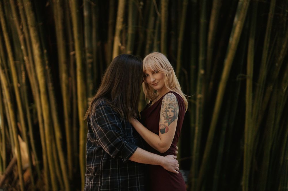 Two people embracing intimately among tall bamboo stalks in atmospheric lighting.