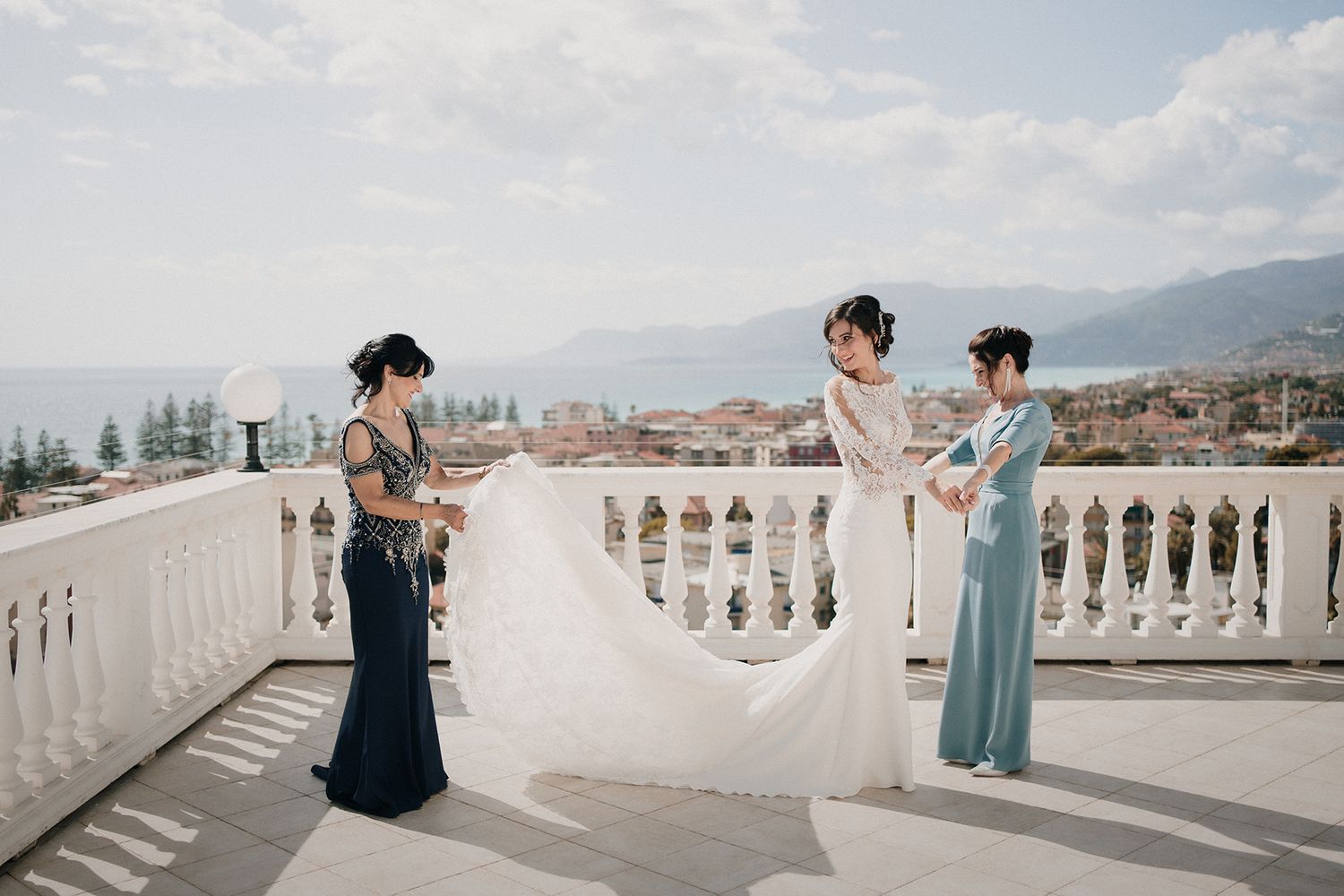 Sposa pronta mentre mamma e testimone sistemano l’abito durante la preparazione – fotografo matrimonio Liguria