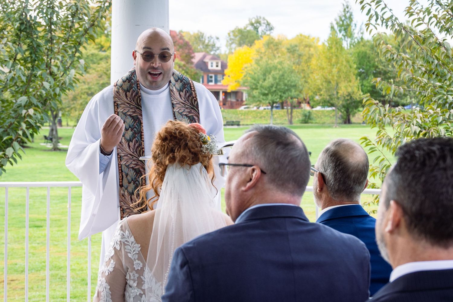frederick maryland wedding photographer Outdoor wedding ceremony with guests seated on white chairs under autumn trees.