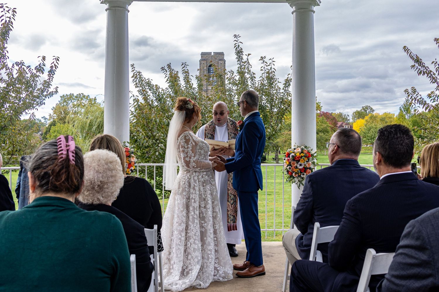 frederick maryland wedding photographer Outdoor wedding ceremony under white columns with guests seated and autumn foliage in background.