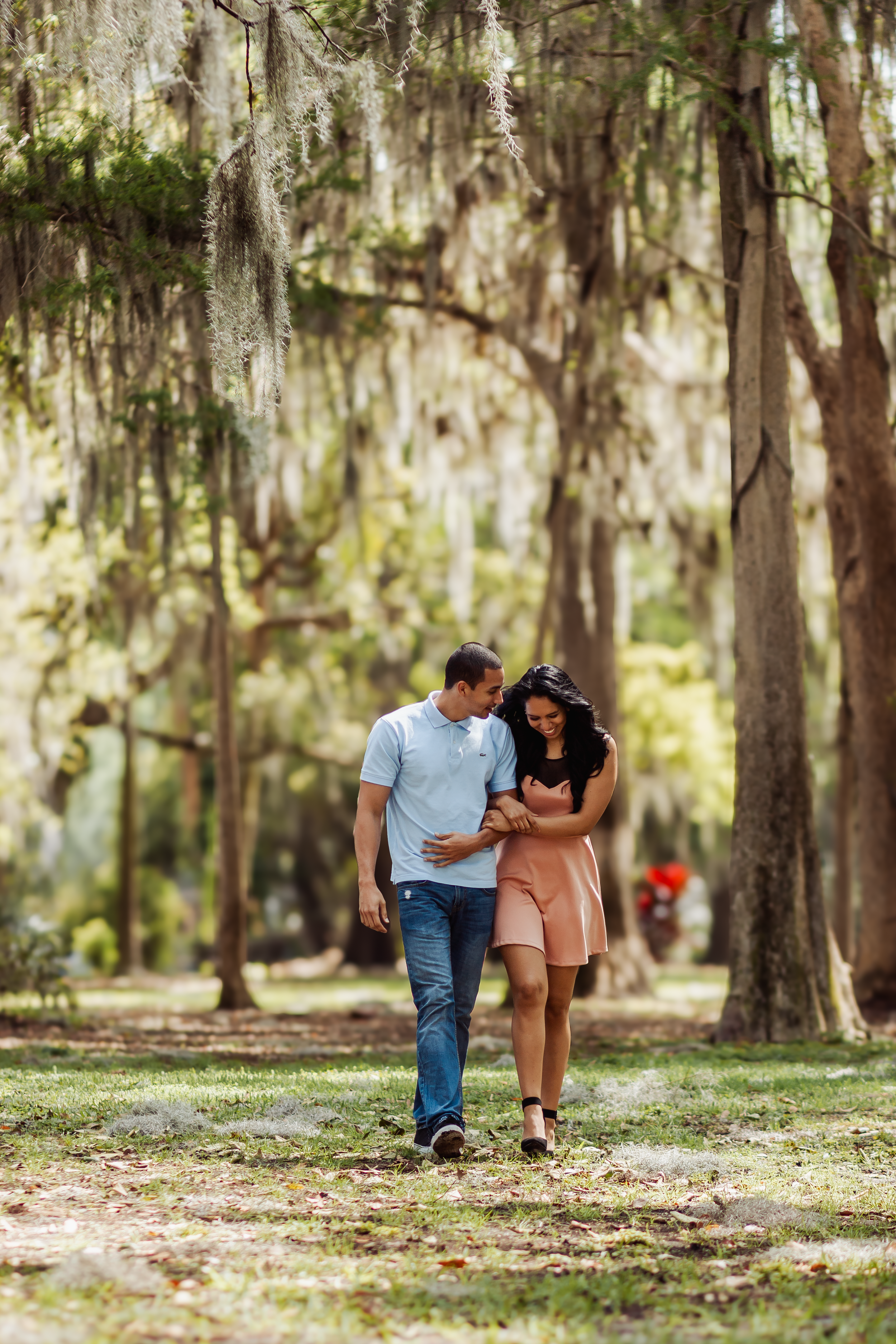 Romantic engagement photos under moss-draped trees in a natural park setting.
