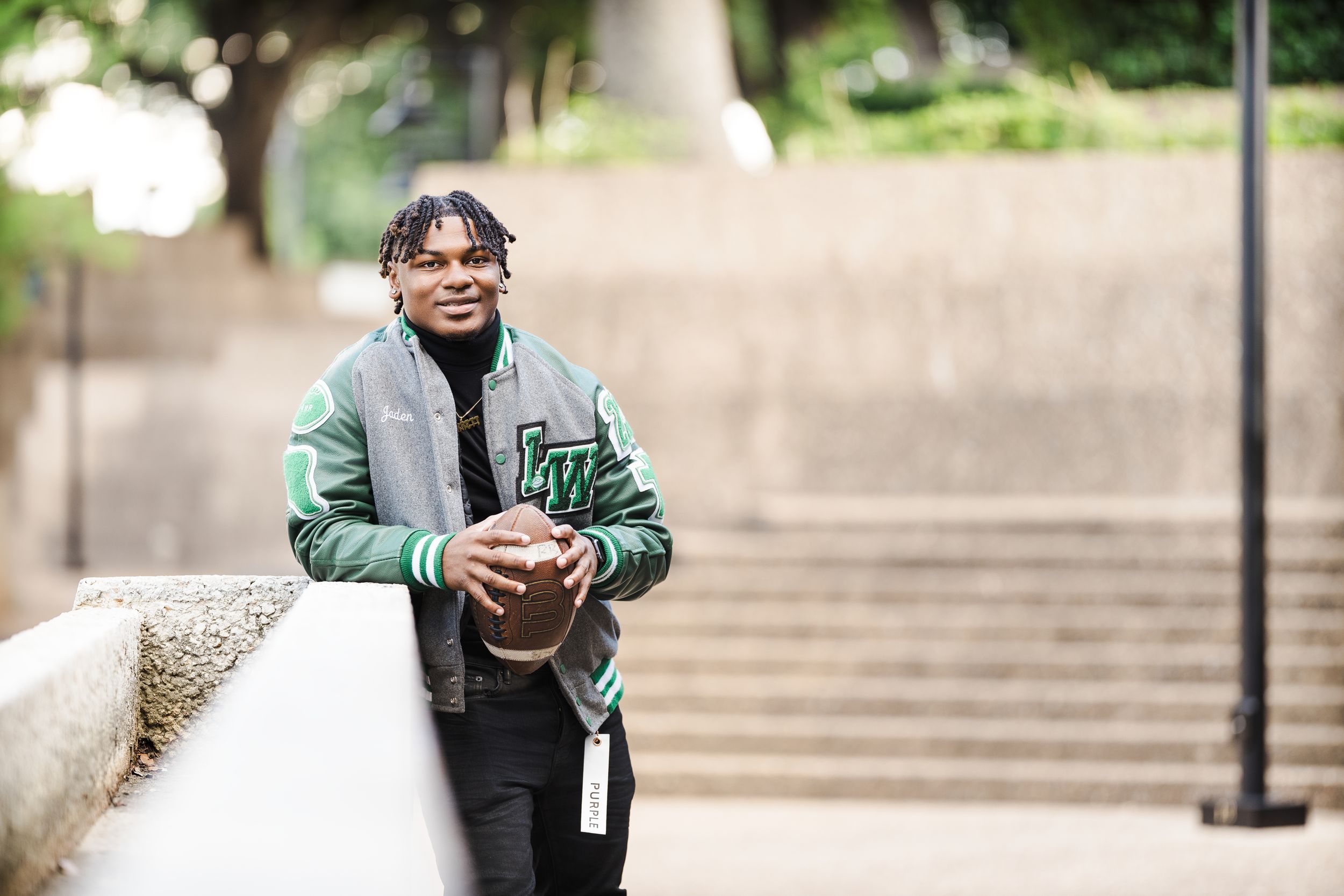 Person in green jacket sitting on concrete steps in an outdoor urban setting.