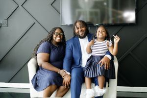 Family relaxing together on couch during casual indoor photo session.